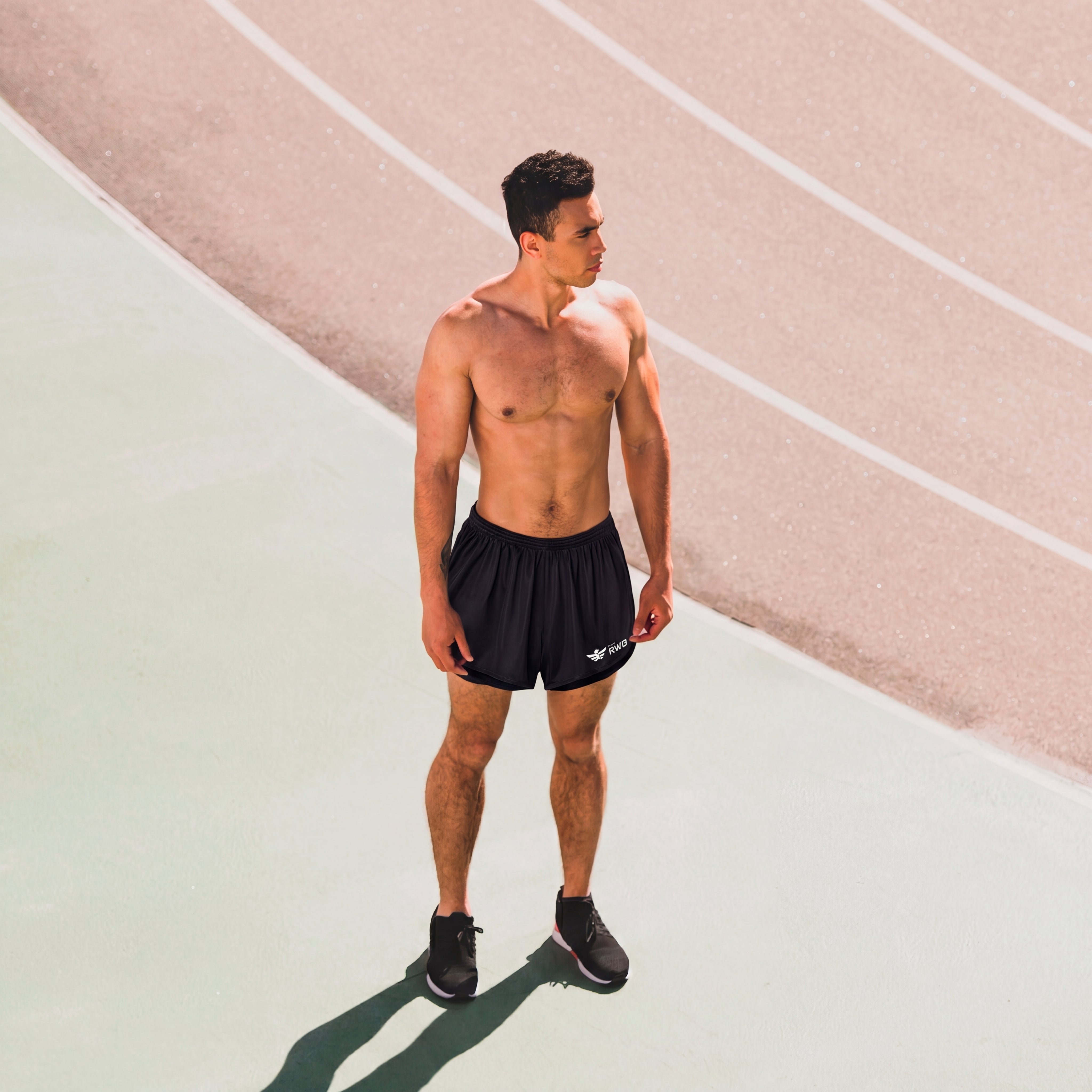 Man in black athletic shorts standing on a track