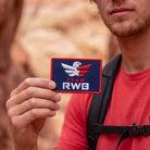 Person holding a 'Team RWB' patch with a blurred background