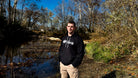 Man wearing black Team RWB hoodie outdoors in a wooded setting, front view showing Eagle graphic