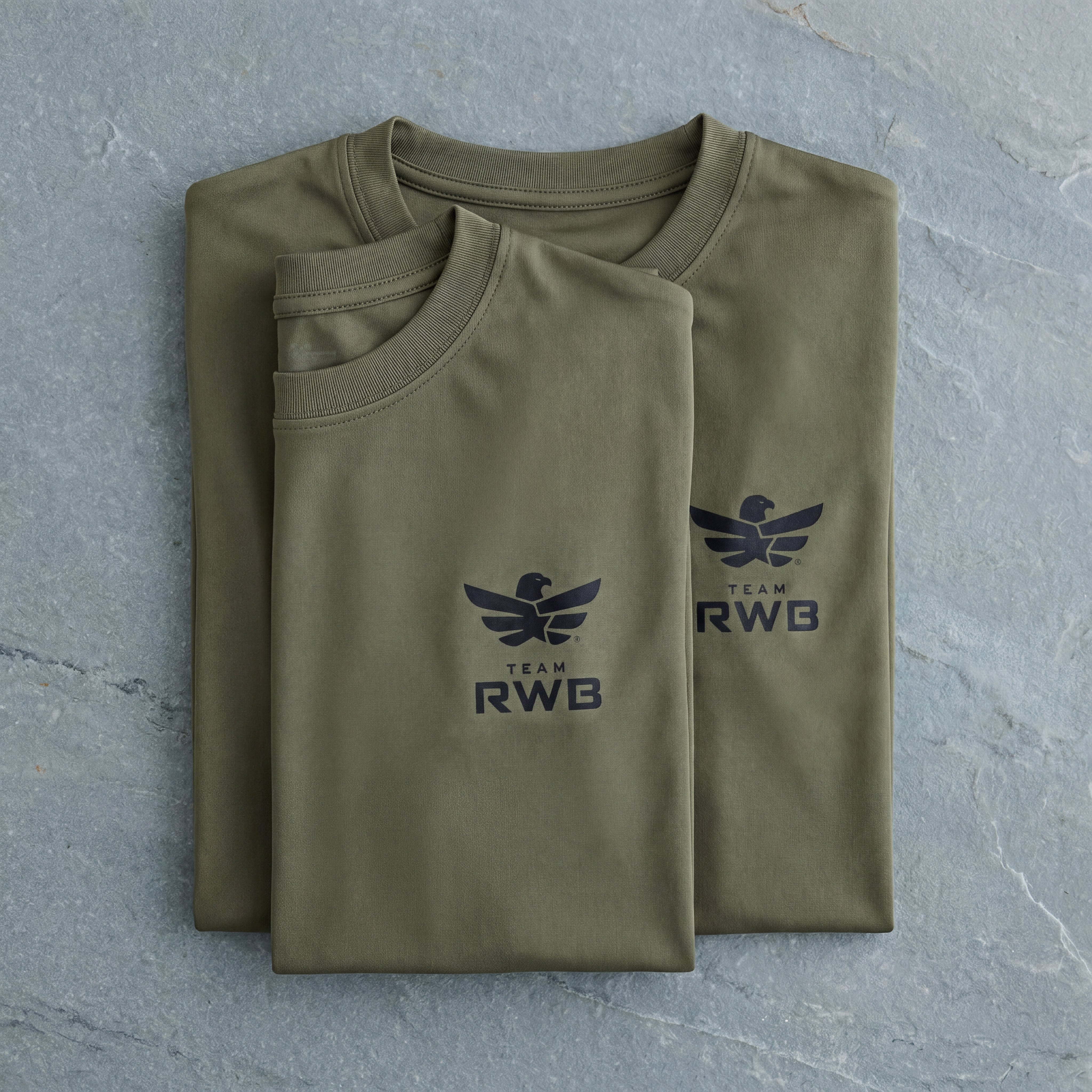 Folded green t-shirt with 'RWB' logo on a gray surface