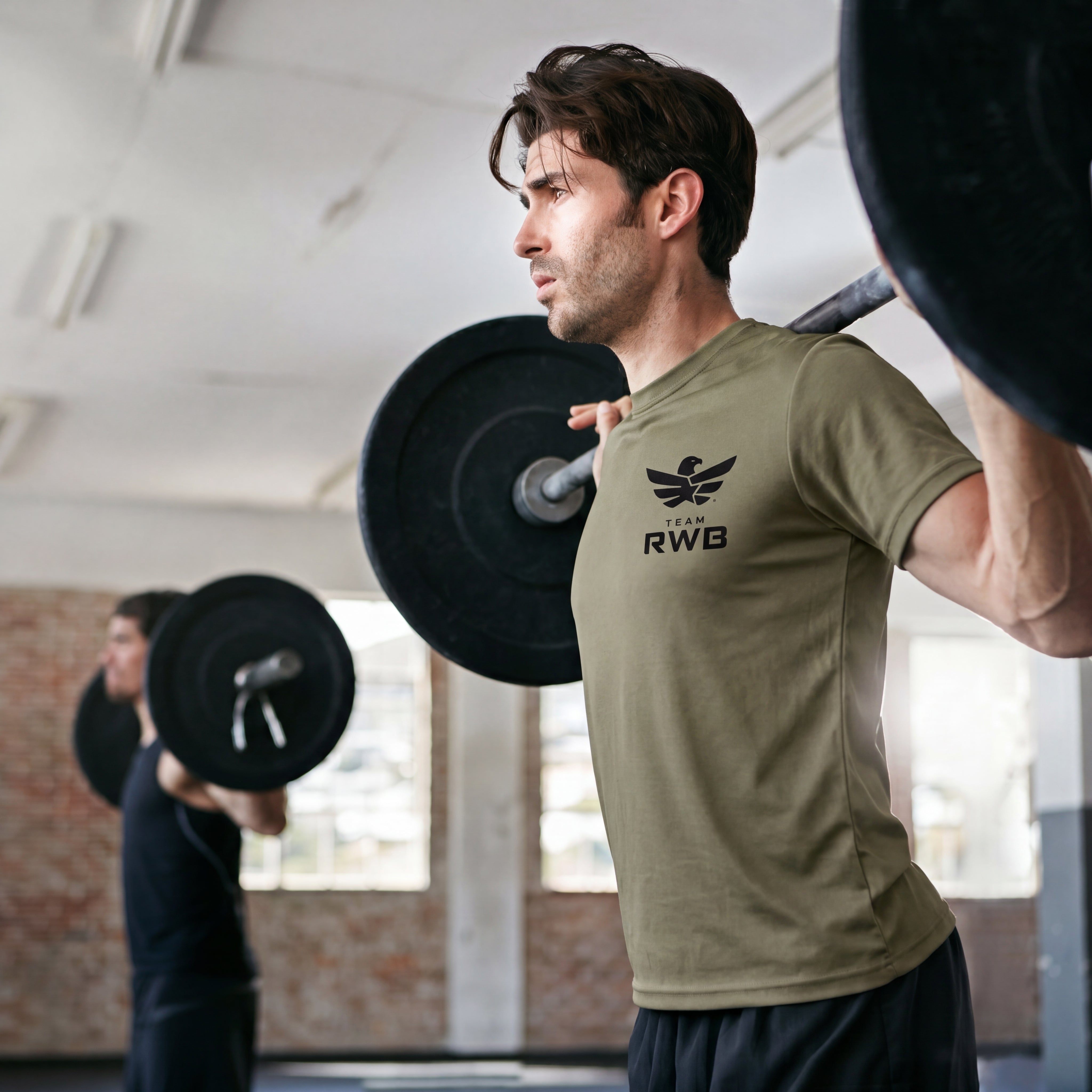 Man lifting weights with a 'RWB' branded shirt in a gym setting